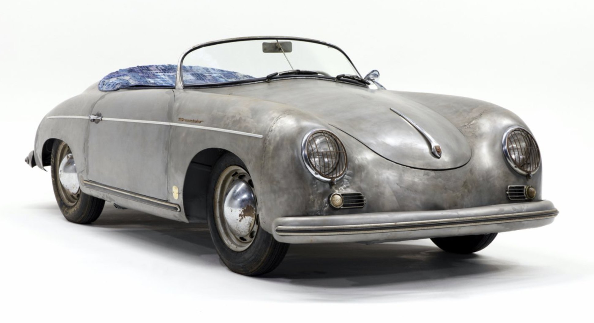 The 356 Bonsai, a 1955 Porsche 356 Speedster in bare, weathered metal with indigo patchwork seats, on a white studio floor